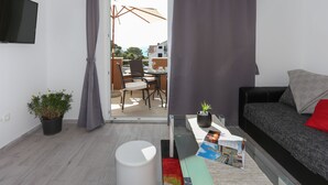 A modern living room with a sofa, a coffee table, and a TV mounted on the wall. - Apartments Bruno (Okrug)