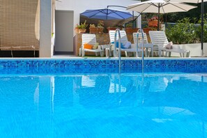 A clear blue pool with lounge chairs and umbrellas. - Apartments Bruno (Okrug)