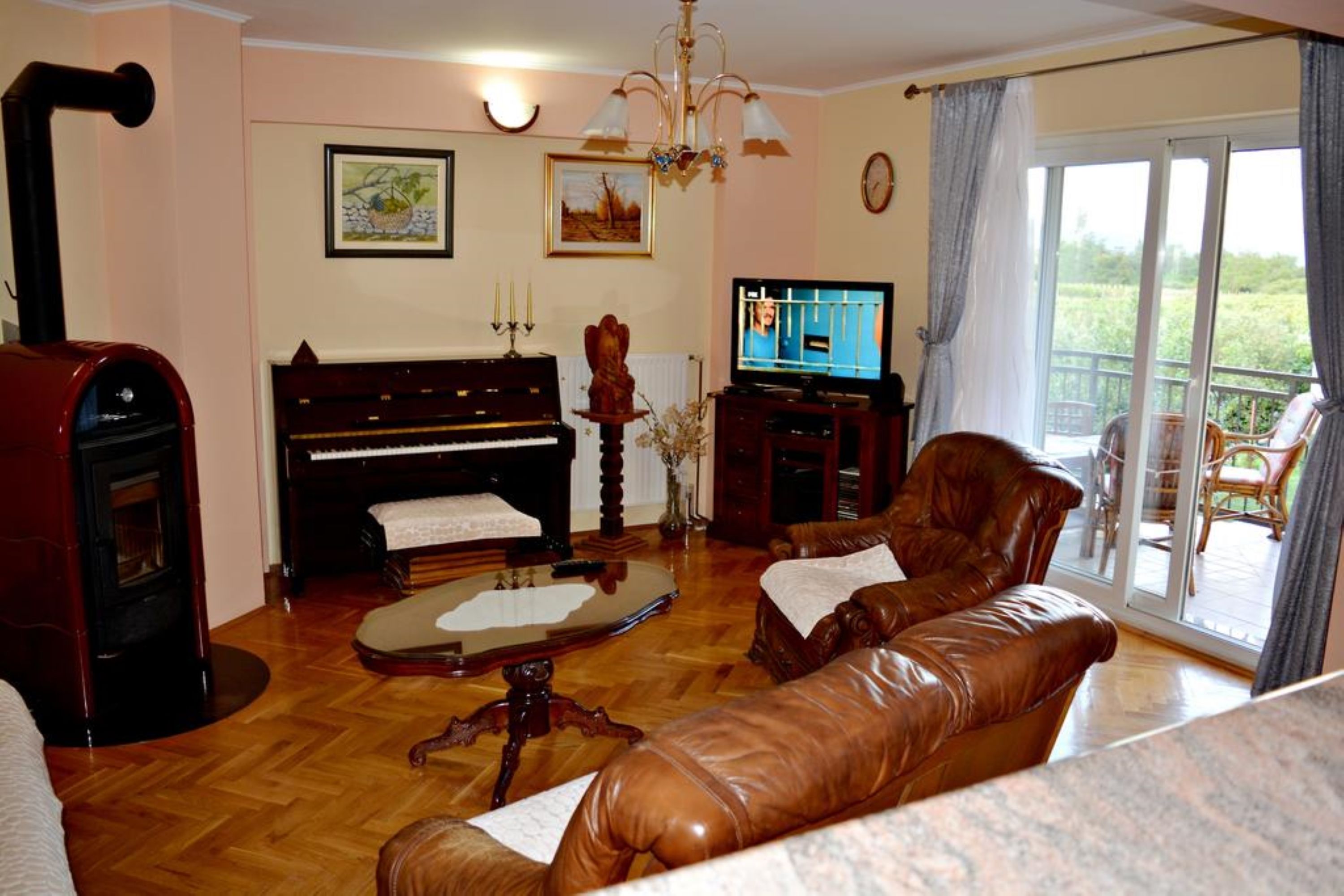 A living room with a piano, leather sofa, and a television.