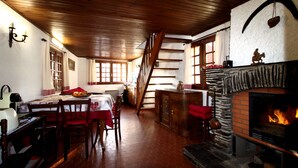 A cozy room with a fireplace, wooden ceiling, and a staircase leading to another level.