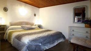A bedroom with a bed, bedside lamps, a dresser, and a mirror.
