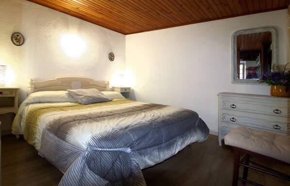 A bedroom with a bed, bedside lamps, a dresser, and a mirror. - Cozy mountain village house. (Estavar)