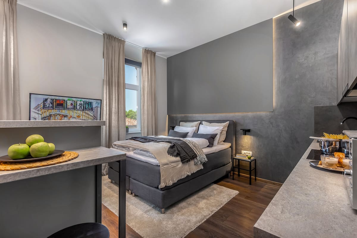 A modern bedroom with a bed, bedside table, and a view of the outdoors.