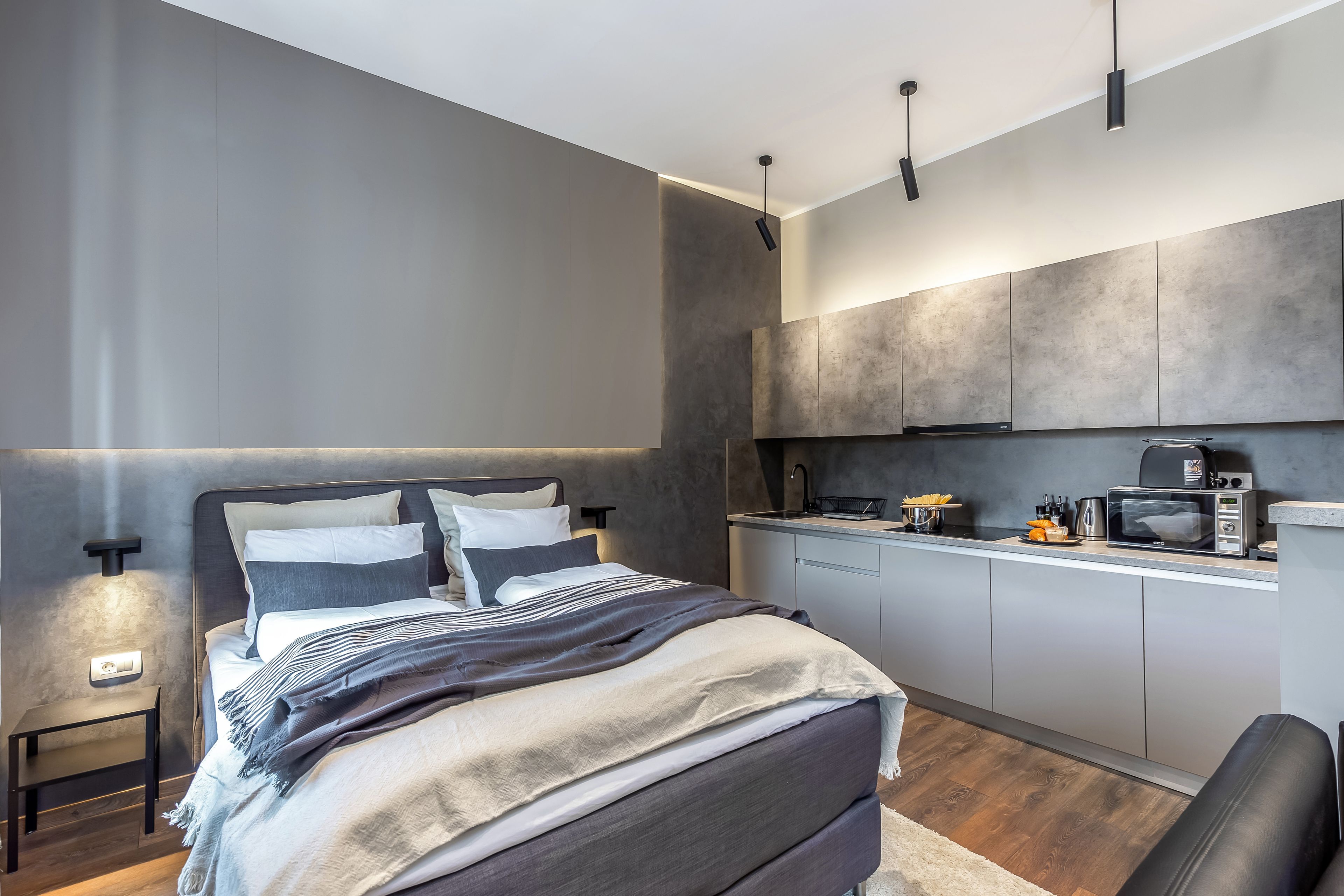 Une chambre moderne dotée d’un grand lit, de tables de chevet et d’un coin cuisine avec un four à micro-ondes et une machine à café.