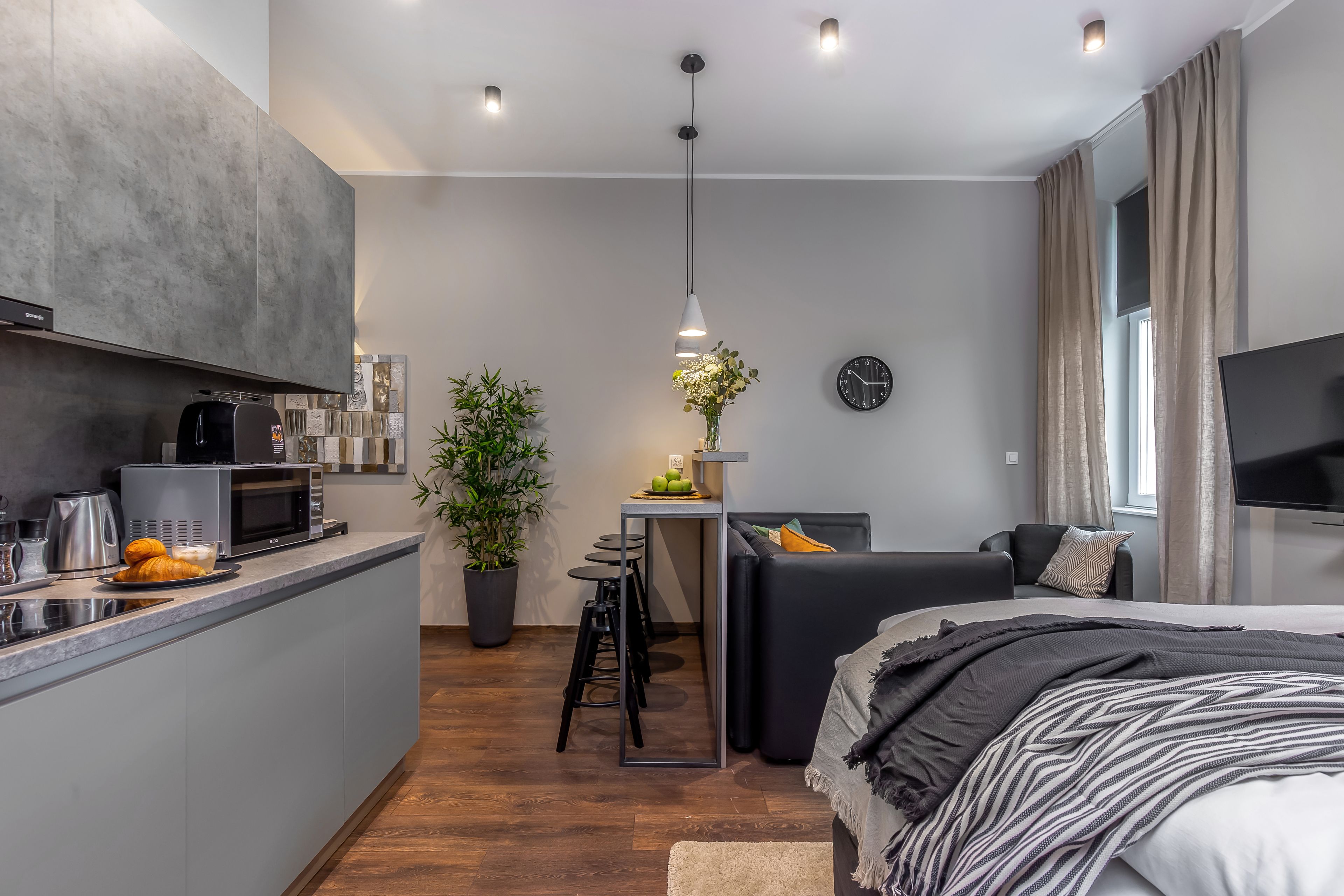 Un espacio habitable moderno y funcional con kitchenette, comedor y dormitorio.