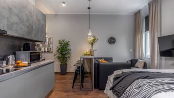 Un espacio habitable moderno y funcional con kitchenette, comedor y dormitorio.