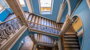 Una imponente escalera con barandillas de metal decorativas y una pared azul.