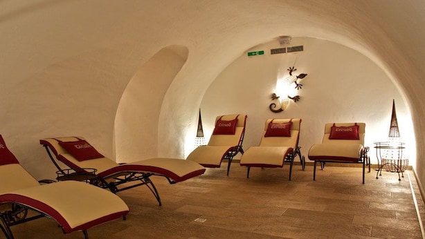 Un solárium con cuatro sillones de descanso, cada uno con un cojín rojo que dice "Crabe". La habitación tiene un techo abovedado y piso de madera.