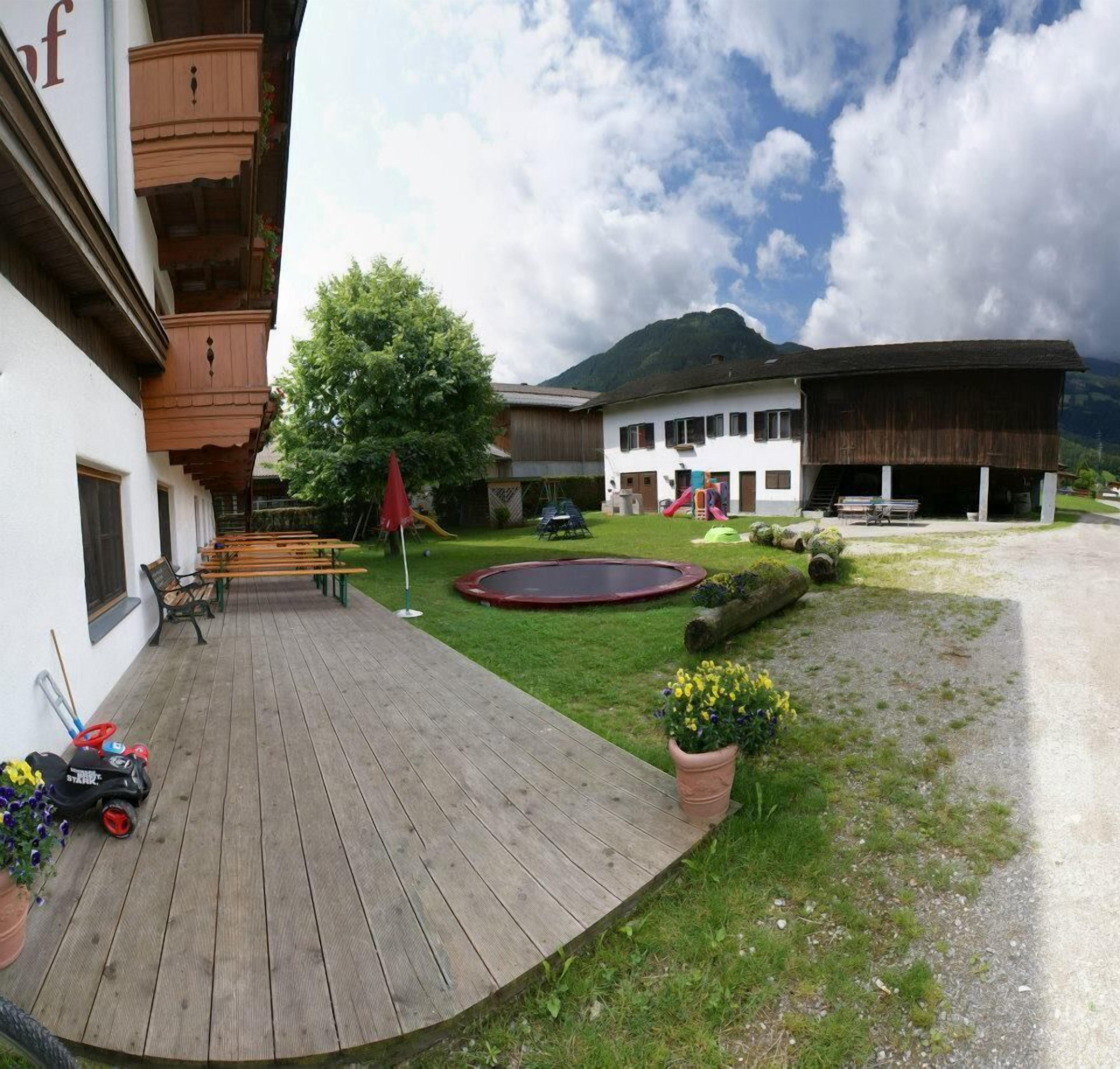 A courtyard with a wooden deck, benches, a playground, and a building with a mountain backdrop.