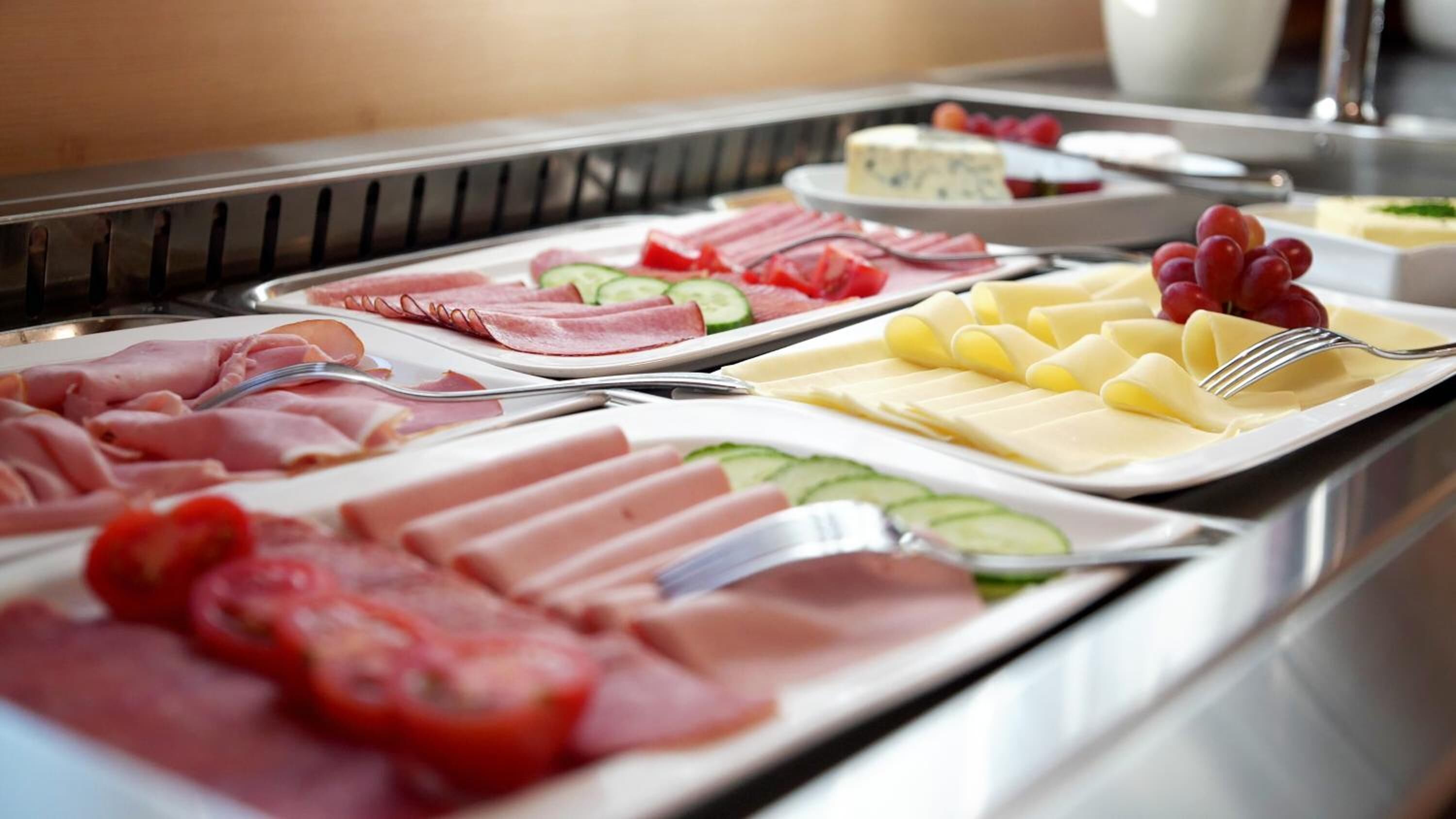 A buffet with various food items including meats, cheeses, and fruits.