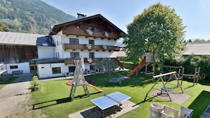 Un hotel con parque infantil, mesa de ping pong y un gran árbol.