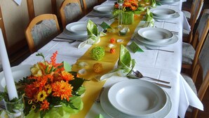 A long dining table set with white plates, silverware, and decorative elements like flowers and a yellow runner. - Pension Birgit (Todtnau)