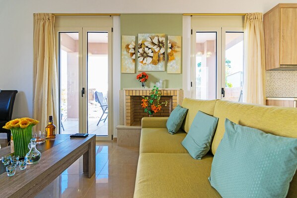 A living room with a sofa, a coffee table, a fireplace, and a view of the outside.