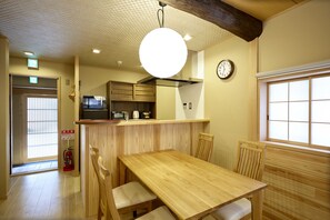 A wooden dining area with a table and chairs, a microwave, and a clock on the wall. - 2bedrooms Kyomachiya Near Kyoto station-Max 9P (京都市)