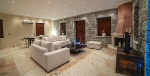 A modern living room with a stone accent wall, a fireplace, and a flat-screen TV.