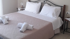 A neatly made bed with white linens and towels, a bedside table with a lamp, and a modern headboard. - VILLA ANDREAS Family- friendly & friends- friendly (Καραβόμυλος)