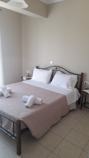 Un lit bien fait, avec du linge de lit et des serviettes blanches, une table de chevet avec une lampe et une tête de lit moderne.