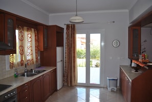Una cocina con un lavamanos, armarios, un refrigerador y un cubo de basura.