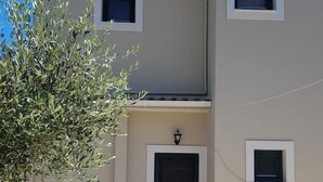 A two-story building with a flat roof, a front door, and three small windows. - VILLA ANDREAS Family- friendly & friends- friendly (Καραβόμυλος)