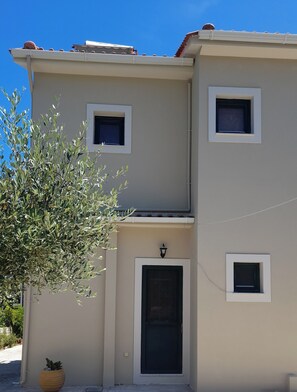 Un edificio de dos pisos con techo plano, una puerta principal y tres ventanas pequeñas.