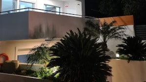 Ein modernes, zweistöckiges Gebäude mit Balkon und einem gut beleuchteten Eingang.