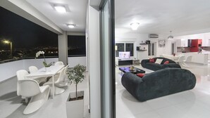 Ein moderner Wohnraum mit Essbereich, einer Couch und einer durchgehenden Tür sichtbaren Küche.
