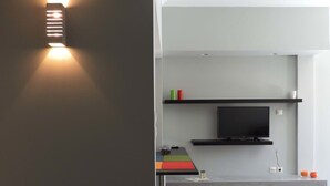 Uma cozinha moderna com televisão integrada, azulejos cinza e design minimalista.