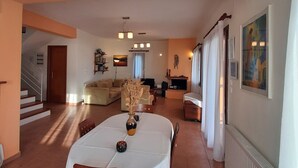 A dining area with a table set for four, a sofa, and a fireplace in the background. - Malena Pool Villa  with stunning view in a quiet location. Free WIFI and jacuz (Γλώσσα)