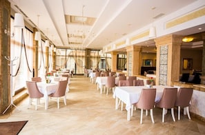 A spacious dining area with multiple tables and chairs, large windows, and a chandelier. - Burgas Beach Resort (Burgas)