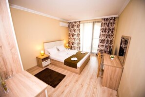 A hotel room with a bed, bedside table, nightstand, dresser, and a mirror. - Burgas Beach Resort (Burgas)
