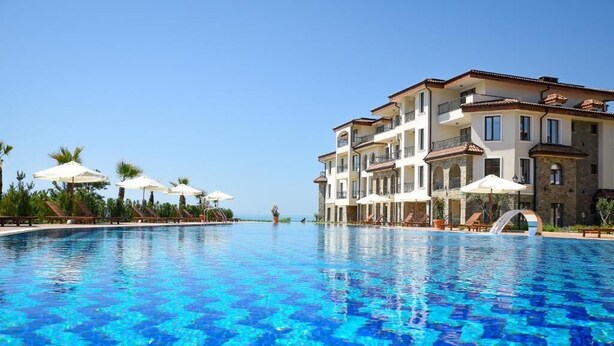Um hotel com piscina, várias varandas e guarda-sóis.