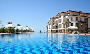 A hotel with a swimming pool, multiple balconies, and outdoor umbrellas. - Burgas Beach Resort (Burgas)