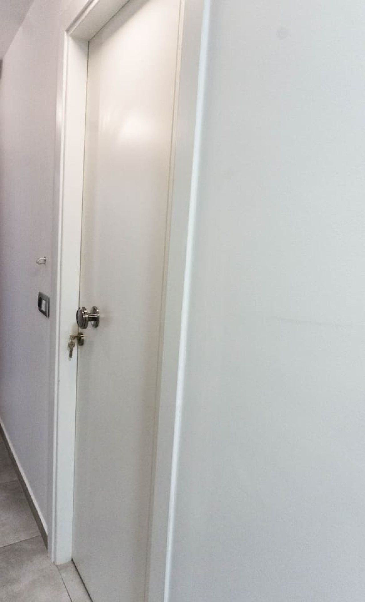 A closed white door with a keyhole and a lock.
