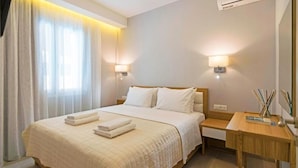 Habitación de hotel con una cama grande, dos mesitas de noche, un escritorio y una ventana con cortinas.