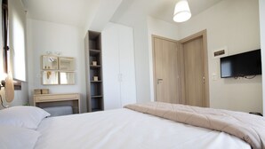 Une chambre à coucher comprenant un lit, un bureau, une armoire, une télévision et un miroir.