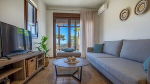 Un salon avec un téléviseur, un canapé et un balcon offrant une vue agréable.