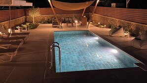 Une piscine extérieure dotée d’une terrasse en bois, de chaises longues et d’un auvent.