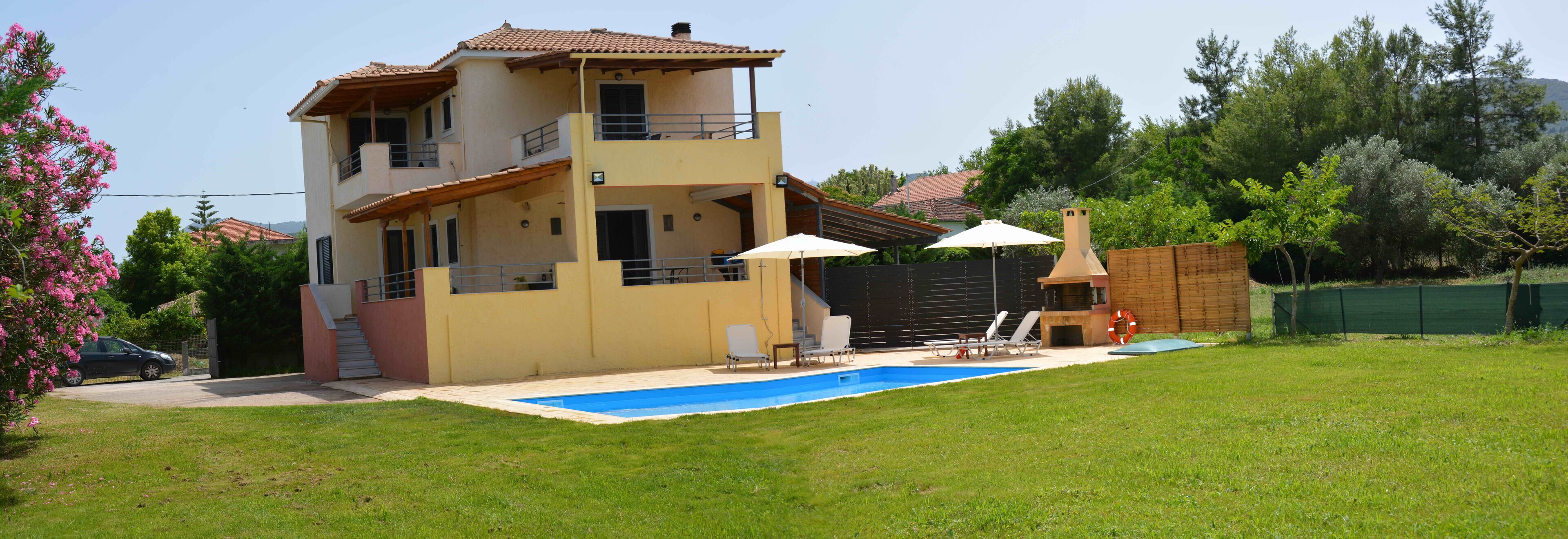 A two-story house with a swimming pool, outdoor seating, and a barbecue area.