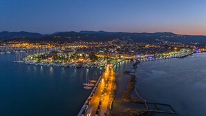 An aerial view of a coastal city at dusk with a marina, waterfront promenade, and a bridge connecting the city to the mainland. - Village Villas Lefkada 2 floor villa, Pool, Large Garden near beaches, & city (Καριώτες)