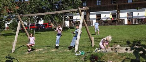 A playground with swings and a building in the background.