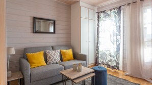A modern living room with a grey sofa, yellow and patterned cushions, a wooden coffee table, and a blue ottoman.
