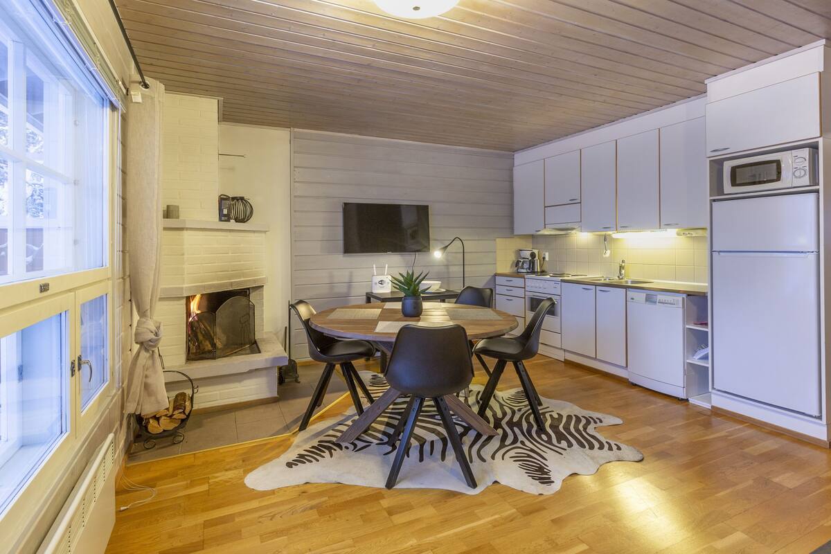 A modern kitchen with white cabinets, a microwave, and a dining area with a zebra print rug.