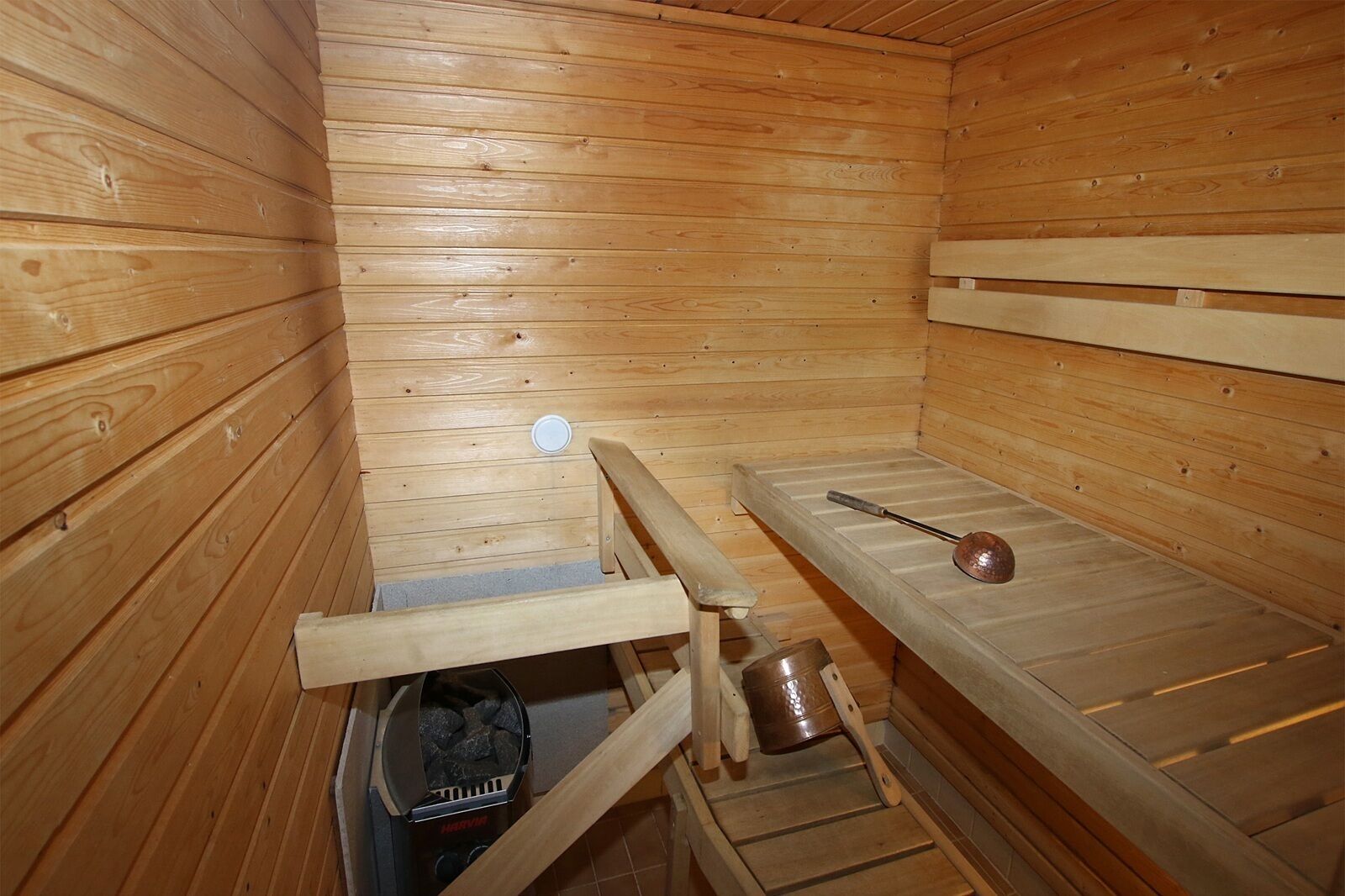 Un sauna avec des murs et des bancs en bois.