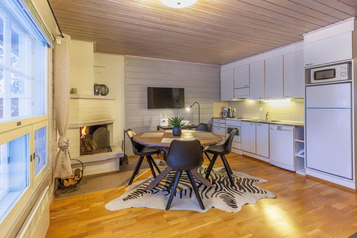 A modern kitchen with white cabinets, a built-in microwave, and a dining area with a zebra-patterned rug.