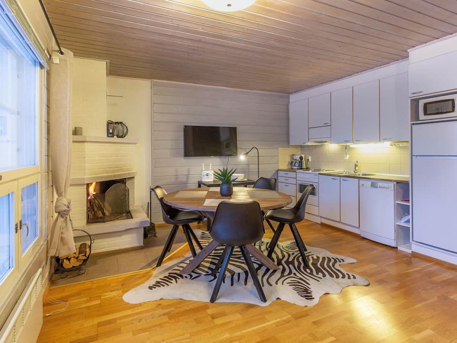 Una cucina moderna con mobili bianchi, un forno a microonde integrato e un'area pranzo con un tappeto a motivi zebrati.