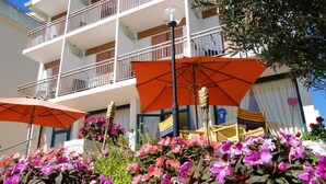 Een meerlaags hotel met balkons, buitenplaatsen en kleurrijke bloemarrangementen.