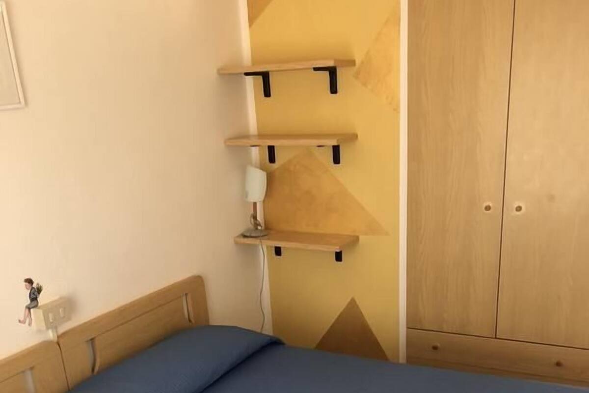 Une chambre à coucher avec un lit, une armoire et un bureau doté d’étagères.