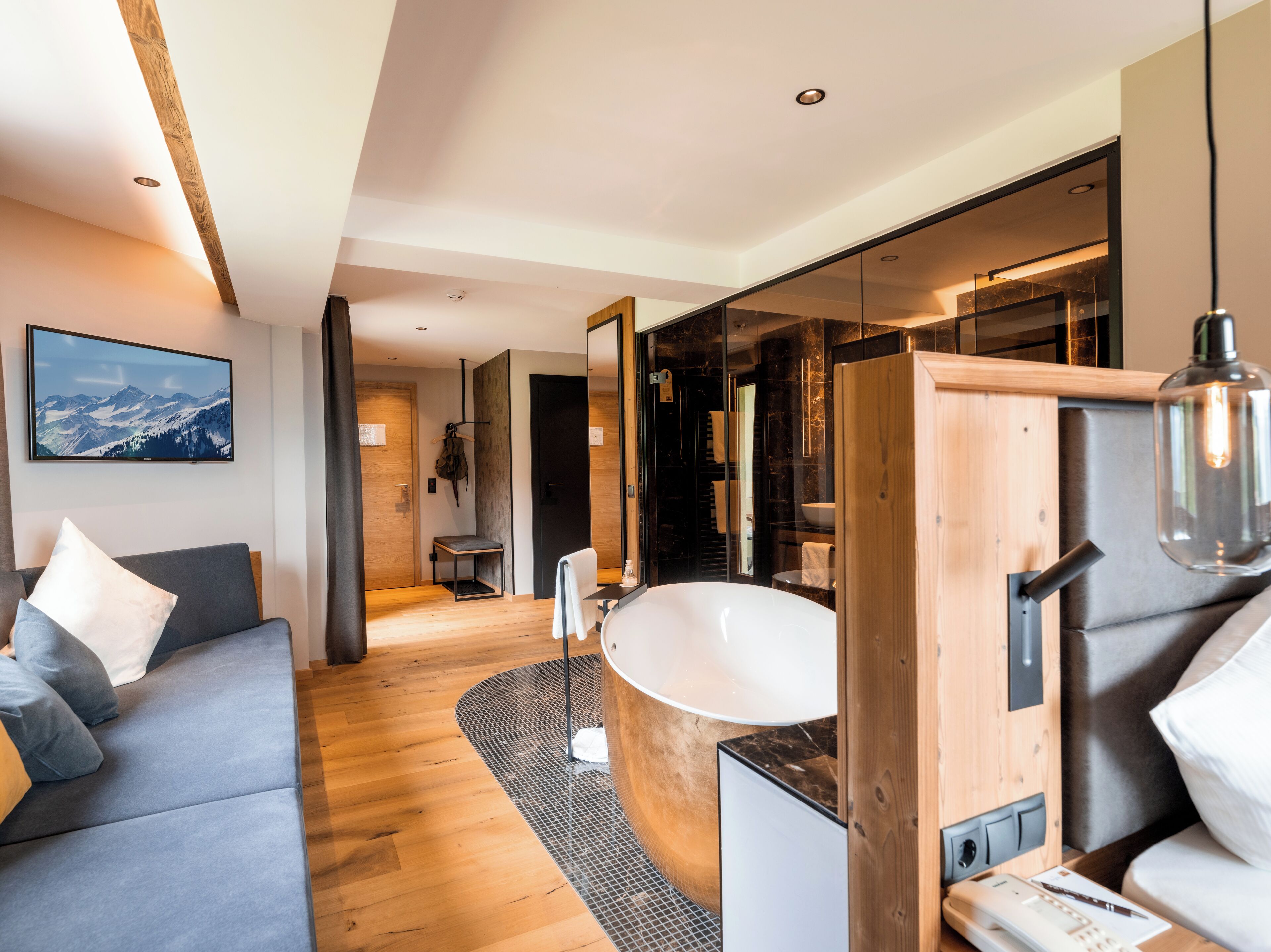 Un baño moderno con una bañera independiente, un tocador de madera y un espejo grande.