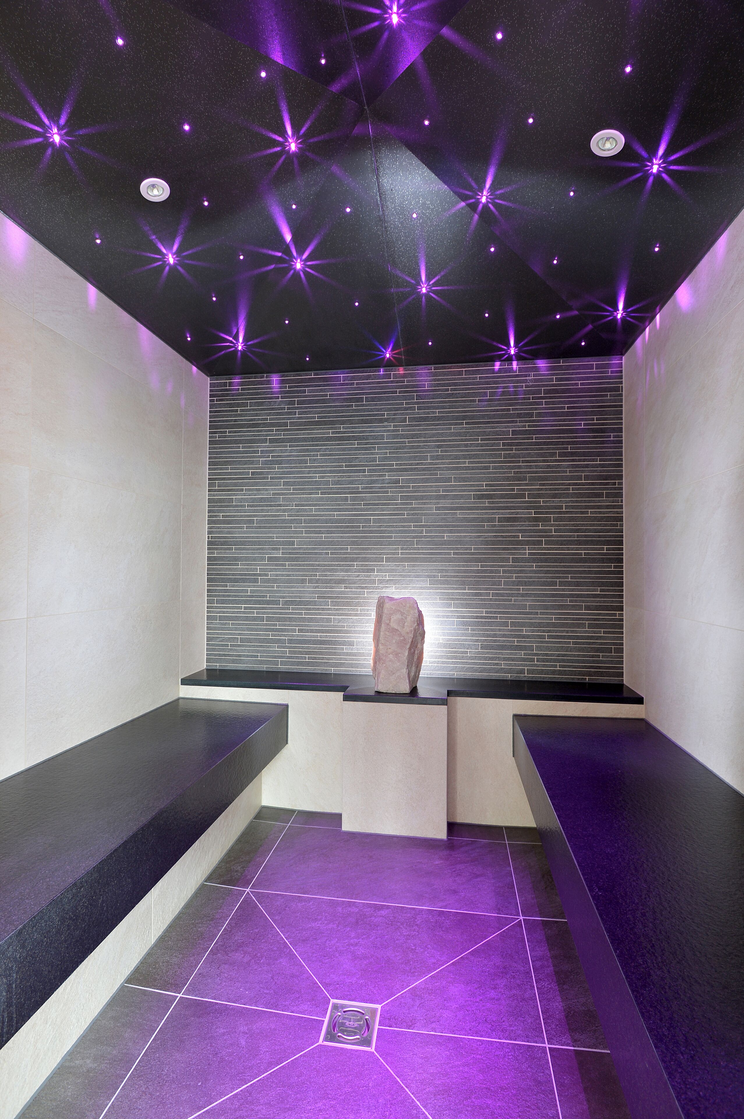 Un moderno spa con techo estrellado, una escultura de piedra y piso de baldosas.