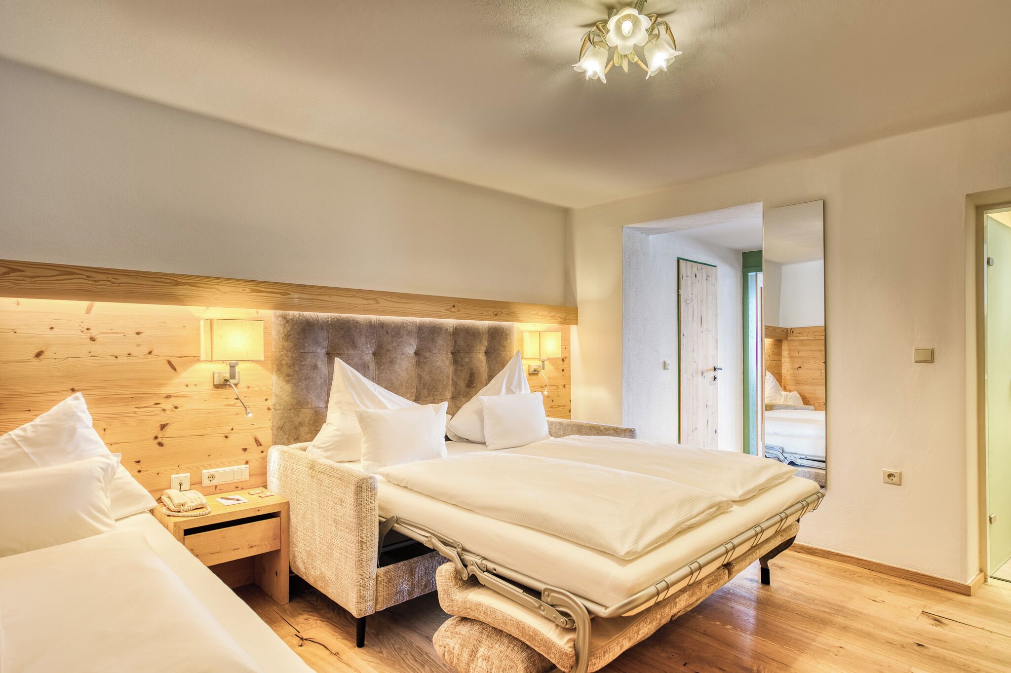 Une chambre d’hôtel avec un grand lit, une tête de lit en bois, des tables de chevet et un miroir.